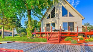 A two-story house with a red deck and a small garden area. - Waterfront Saginaw Bay Retreat w/ Grill & Yard! (Fairgrove)
