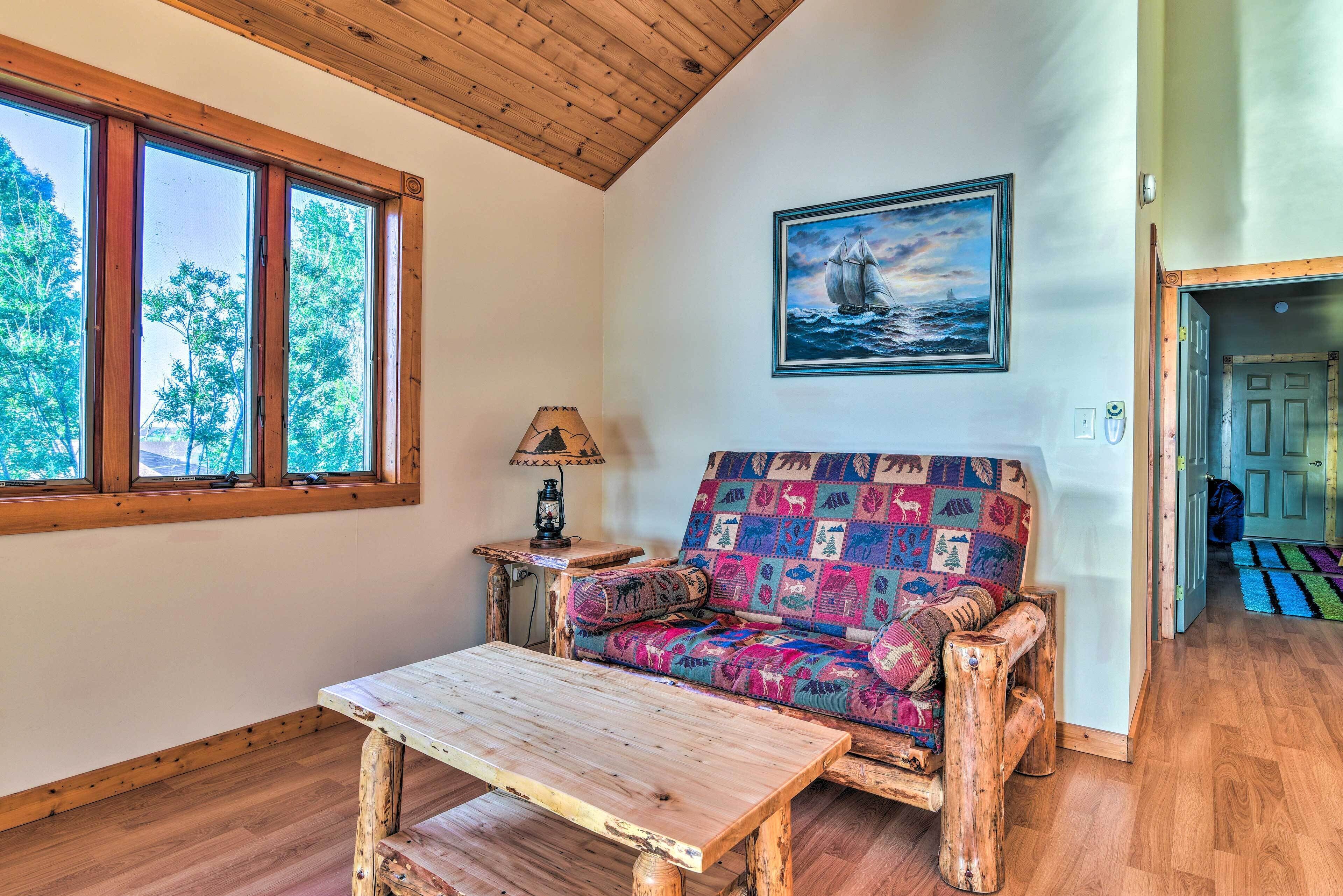 A cozy room with a wooden bench, a colorful sofa, and a painting of a sailboat.