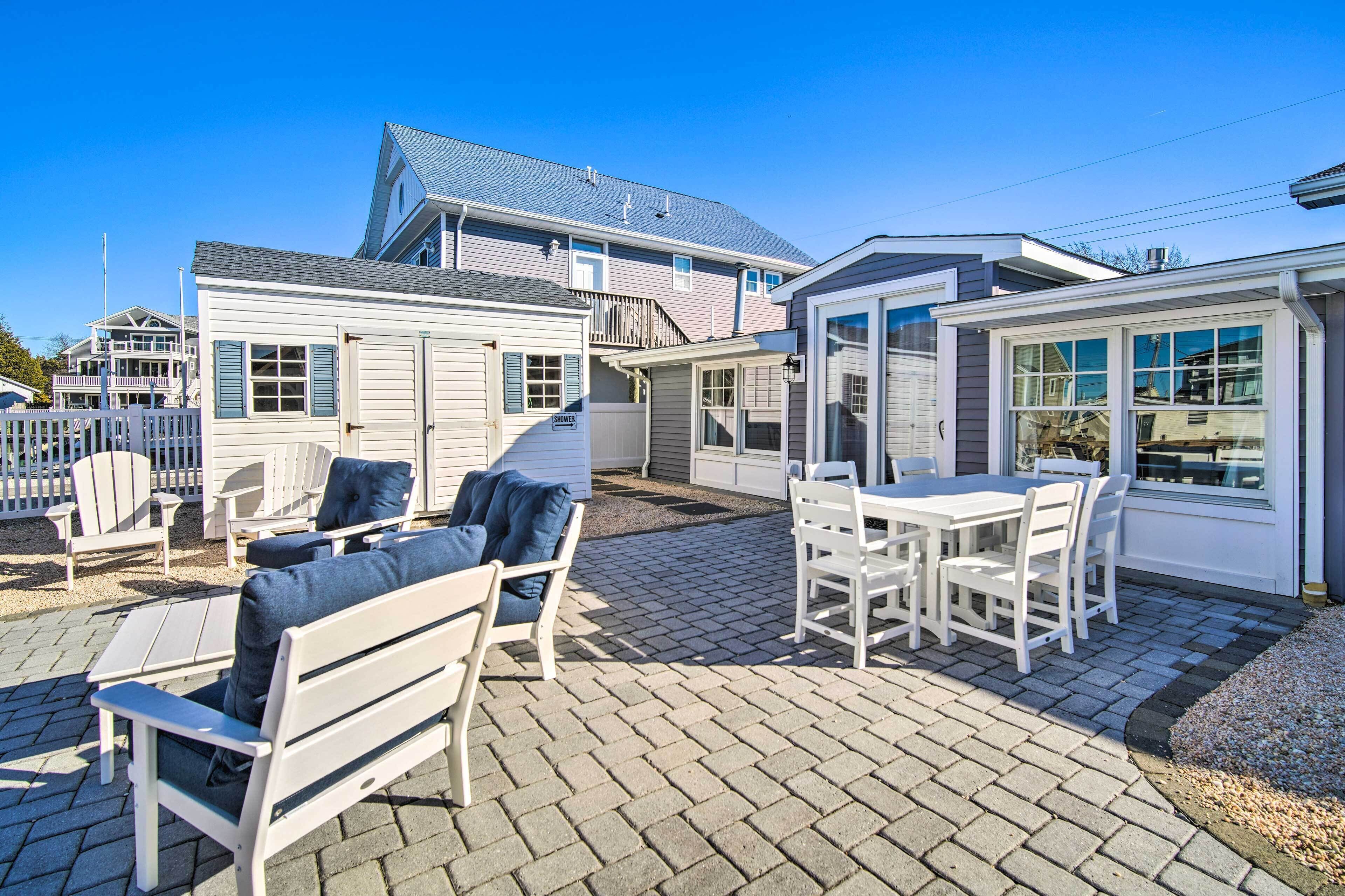 Un patio con mobiliario exterior, incluyendo sillas y una mesa, y una zona de estar cubierta con vista a la casa.