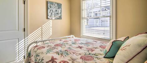 A bedroom with a bed, a window with blinds, a door, and a wall-mounted artwork.