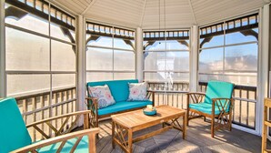 Un solarium con una mesa de madera, sillas color turquesa y un sofá azul con cojines estampados.