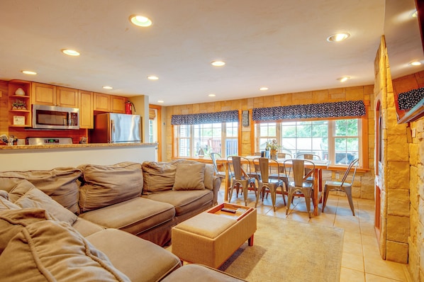 A living room with a sectional sofa, a dining area with a table and chairs, and a kitchen with appliances. - Laconia Home w/ Beach - 1/2 Mi to Weirs Beach (Laconia)