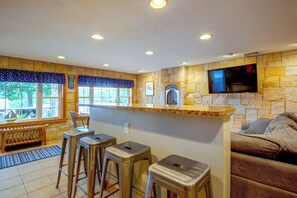 Una cocina moderna con pared de piedra, un televisor de pantalla plana y una zona de bar con taburetes.