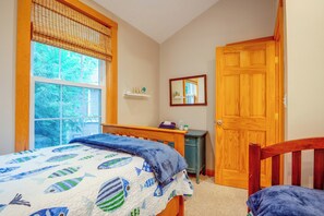 Un dormitorio con cama, mesita de noche, cómoda, ventana con persianas y puerta.
