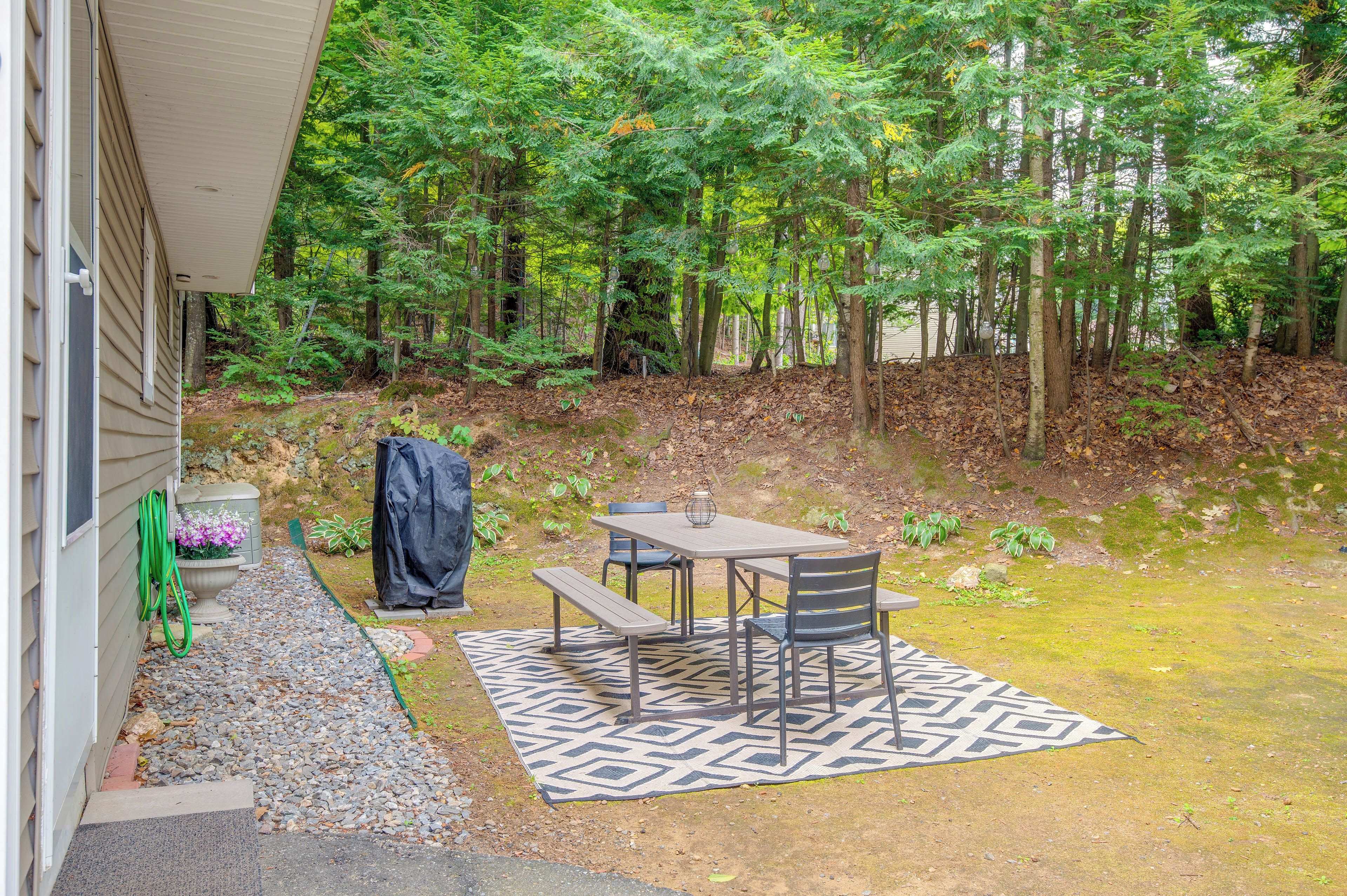 A patio area with a table and chairs, a covered bench, and a potted plant.