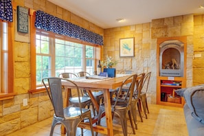 A dining area with a stone wall, a large window, and a fireplace. - Laconia Home w/ Beach - 1/2 Mi to Weirs Beach (Laconia)