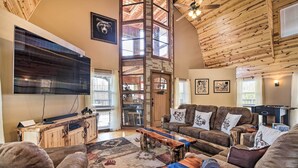 A cozy living room with a large TV, wooden furniture, and a fireplace. - Strawberry Plains Cabin: Private Pond & Game Room! (Kodak)