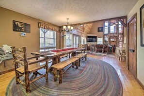 Un vaste espace dédié à la salle à manger, avec des bancs en bois et une grande table, le tout entouré de grandes fenêtres et surmonté d’un haut plafond.