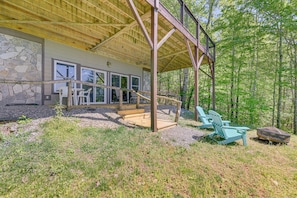 A covered outdoor area with Adirondack chairs, a stone wall, and a wooden deck. - Sweeping Smoky Mountain Views: Bella Vista' Cabin (Whittier)