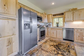 A kitchen with wooden cabinets, stainless steel appliances, and a patterned rug. - Sweeping Smoky Mountain Views: Bella Vista' Cabin (Whittier)