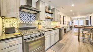 A modern kitchen with stainless steel appliances, patterned backsplash, and light wood flooring. - Pittsburgh Home: Walkable Location! (Pittsburgh)