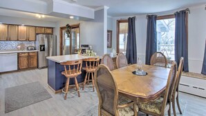 A kitchen with wooden cabinets, a refrigerator, and a dining area with a wooden table and chairs. - 5 Mi to Point Beach State Forest: Home w/ Fire Pit (Two Rivers)