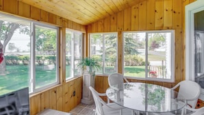 A wooden-paneled room with a glass table and chairs, large windows, and a potted plant. - 5 Mi to Point Beach State Forest: Home w/ Fire Pit (Two Rivers)