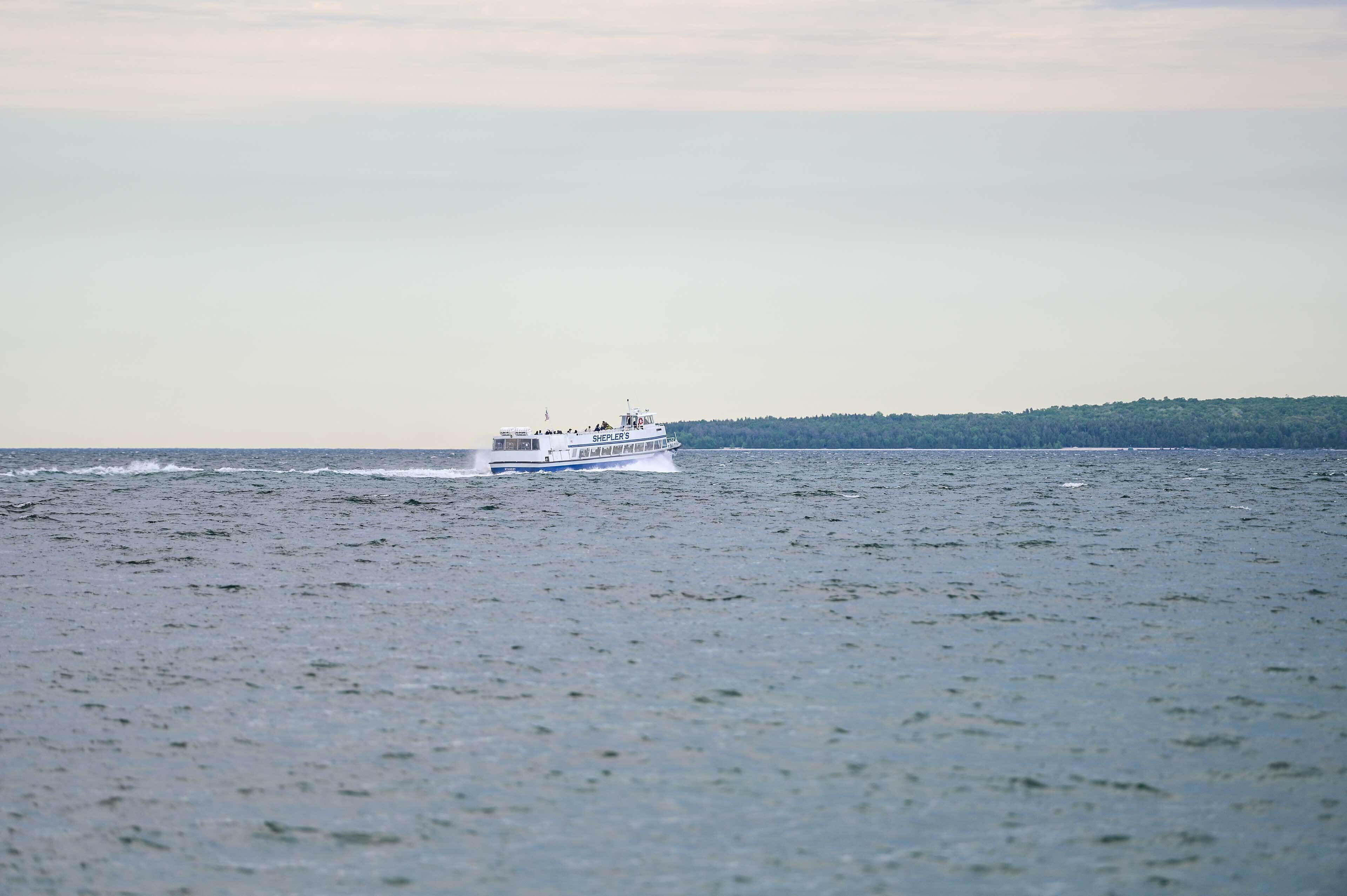 Un barco sobre aguas tranquilas, con una masa terrestre boscosa al fondo.