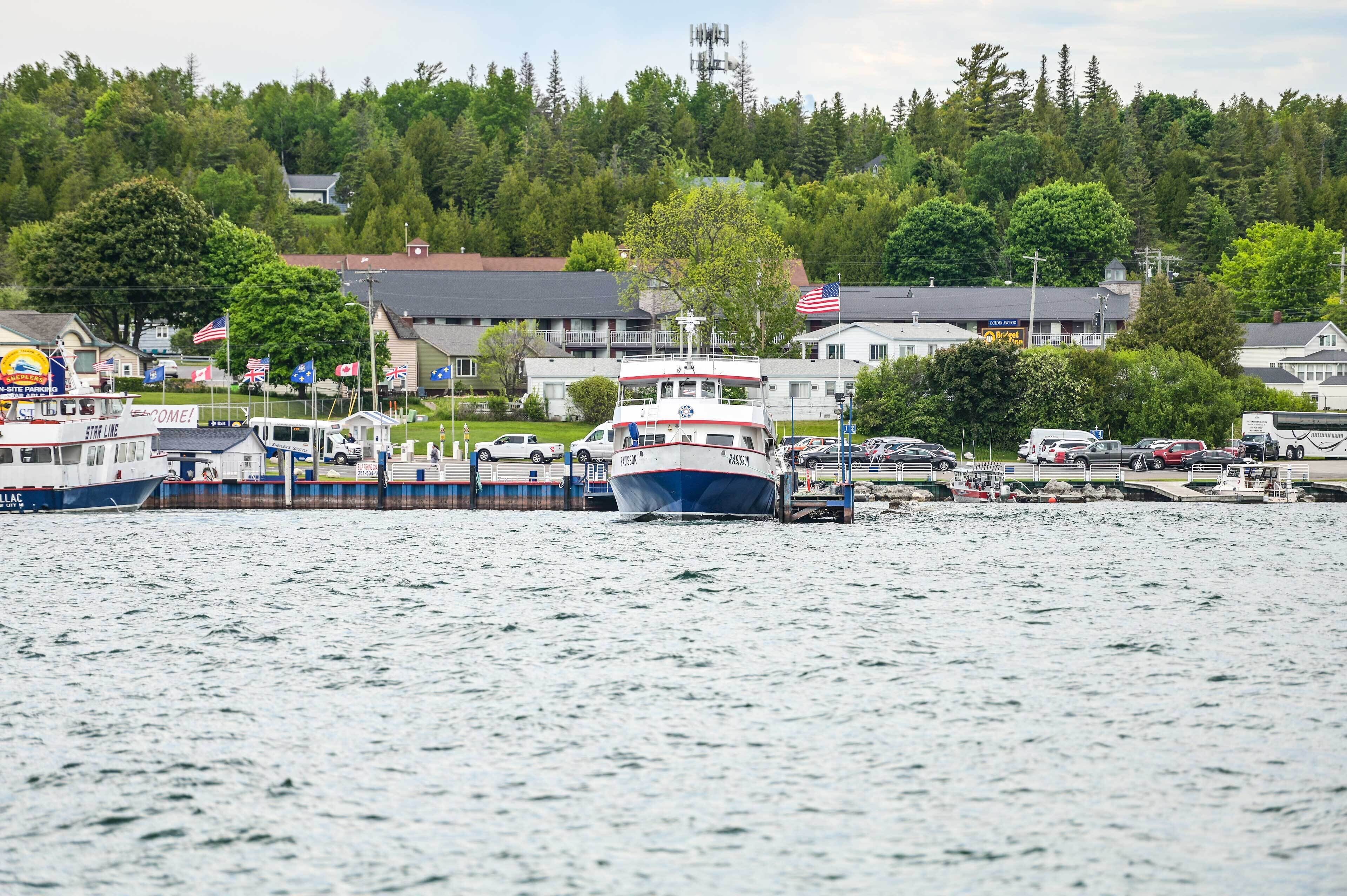 A waterfront area with a docked boat, a marina with several boats, and buildings in the background.