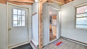 A wooden interior with a white door, a window, and a welcome mat.