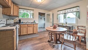 A kitchen with wooden cabinets, a microwave, a stove, and a dining area with a round table and wooden chairs.