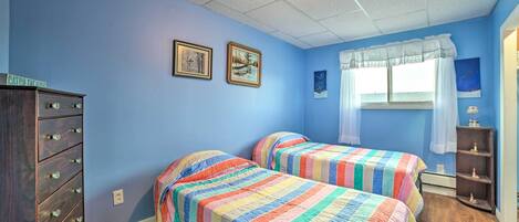 Een slaapkamer met twee bedden, een kaptafel en een raam met gordijnen.