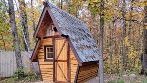 A small wooden cabin with a sloped roof, a front door, and a small porch. - Wooded Mcgrath Home w/ Sauna Near Soo Line Trail! (Mc Grath)