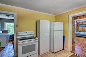 Cuina amb electrodomèstics blancs, una finestra i una porta que dóna a una zona d'estar.