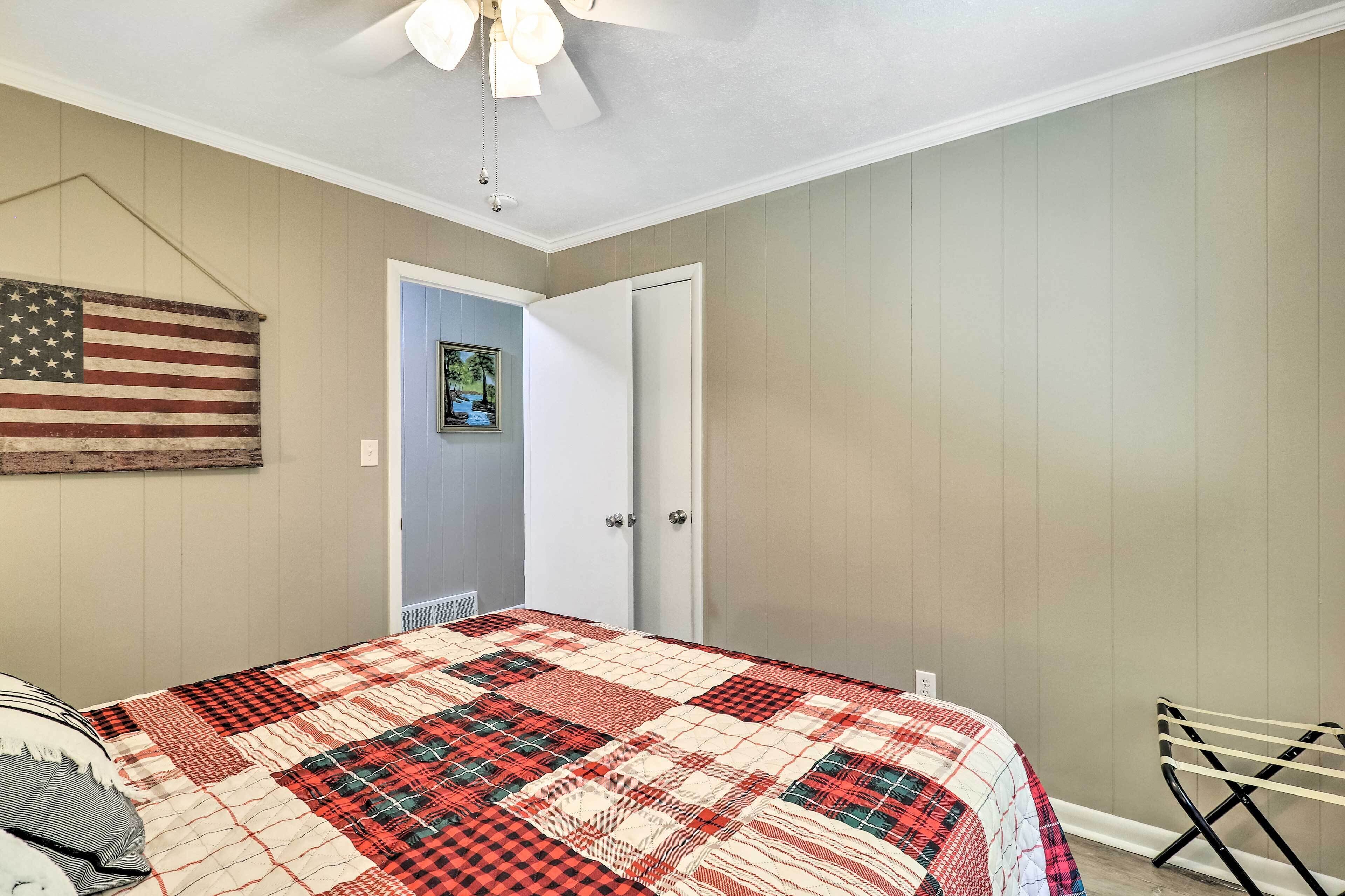 Une chambre à coucher avec un lit, un ventilateur de plafond, une porte et un drapeau américain accroché au mur.