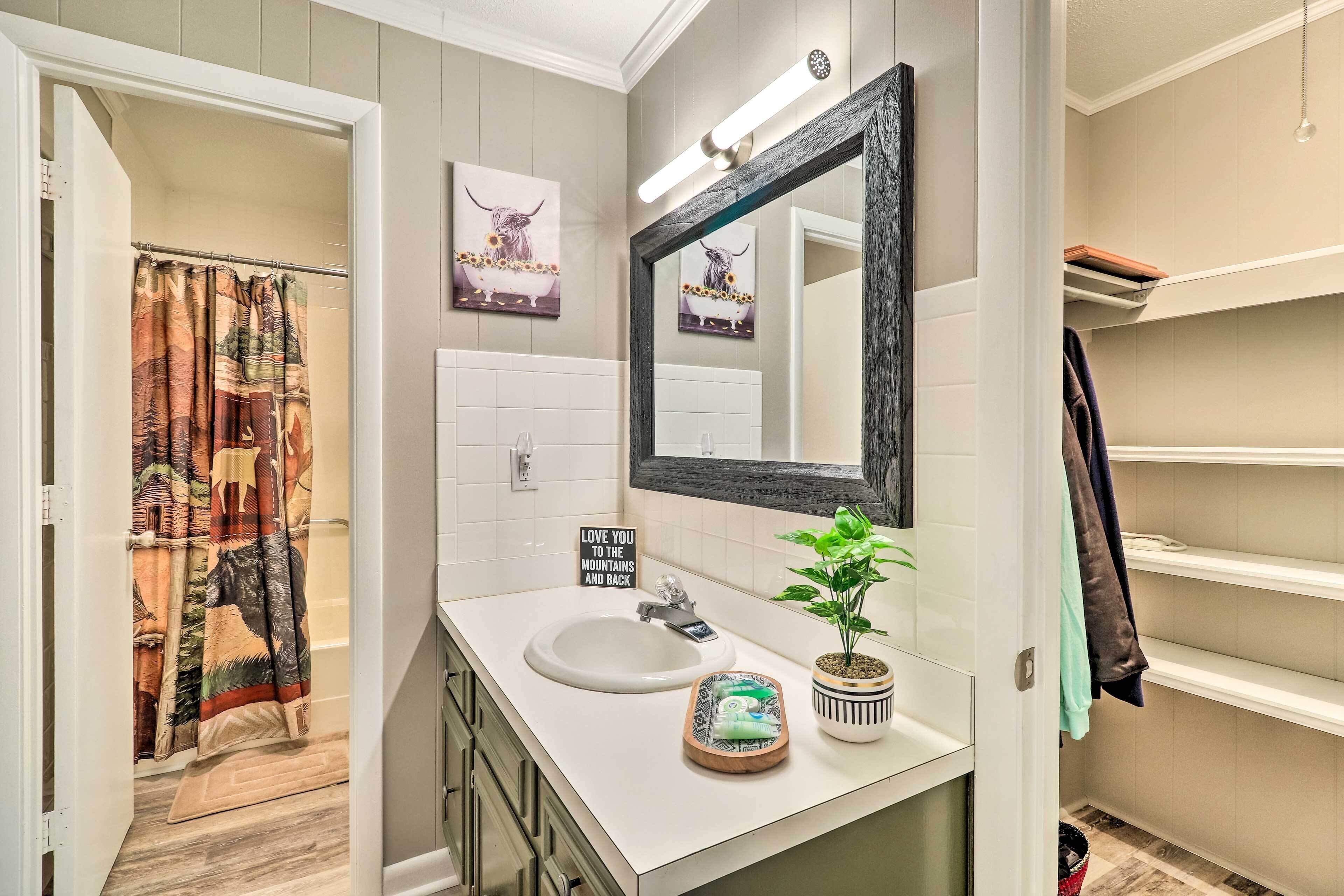 Une salle de bain avec un lavabo blanc, un miroir, une plante en pot et un panneau sur lequel on peut lire : « Je vous aime plus que tout au monde ».