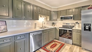 A kitchen with grey cabinets, stainless steel appliances, and a tiled backsplash.
