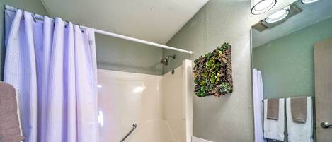 A bathroom with a shower, toilet, sink, and a mirror.