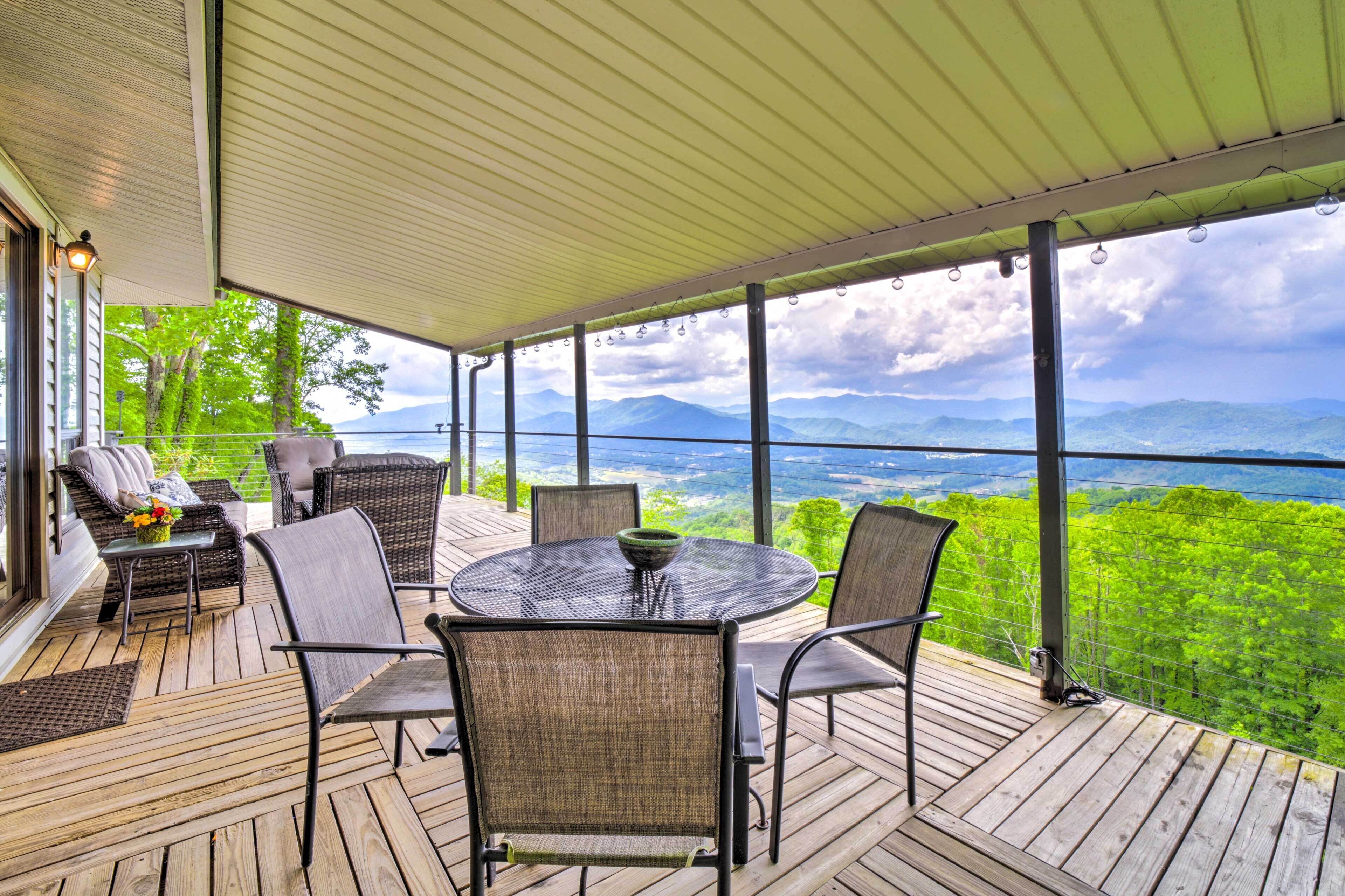Eine überdachte Terrasse im Freien mit Korbmöbeln und einem Tisch, mit Blick auf eine Berglandschaft.