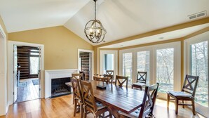 A spacious dining room with a large wooden table, several chairs, a fireplace, and large windows offering a view of the outdoors. - Spacious Prospect Cottage w/ Deck & Scenic Views (Prospect)