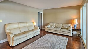 Un salon avec deux canapés en cuir beige, un tapis à motifs et une lampe posée sur une table d’appoint.