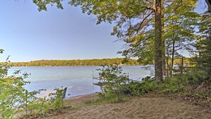 Une vue sur le lac, avec une plage de sable, des arbres et un quai.