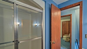 Une pièce dotée d’une porte-fenêtre coulissante, d’une porte en bois et d’un miroir qui reflète une chaise et une porte au fond.