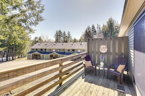 A wooden deck with a bench and a chair, overlooking a row of beach houses with a sign that reads "MT SNOW". - Relaxing Mountain Refuge: 4 Miles to Mt Snow! (West Dover)