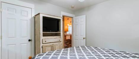A bedroom with a bed, a wardrobe, and a television.