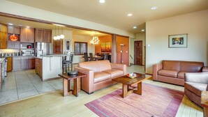 A spacious living area with a sofa, coffee table, and a kitchen in the background. - Upscale Laramie Home w/ Hot Tub & Patio! (Laramie)