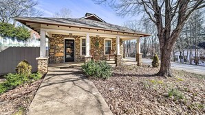 A stone house with a porch, a front door, and a small front yard with a tree and shrubs. - Quaint Home w/ Porch in Downtown Waynesville! (Waynesville)