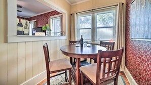 A dining area with a round wooden table, four chairs, and a window with blinds. - Quaint Home w/ Porch in Downtown Waynesville! (Waynesville)