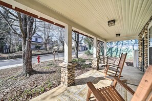 A covered porch with stone pillars, wooden chairs, and a patterned floor. - Quaint Home w/ Porch in Downtown Waynesville! (Waynesville)