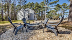 A house with a stone fire pit and Adirondack chairs in a forested area. - Pet-friendly Home: Spacious Yard + Community Perks (Montross)