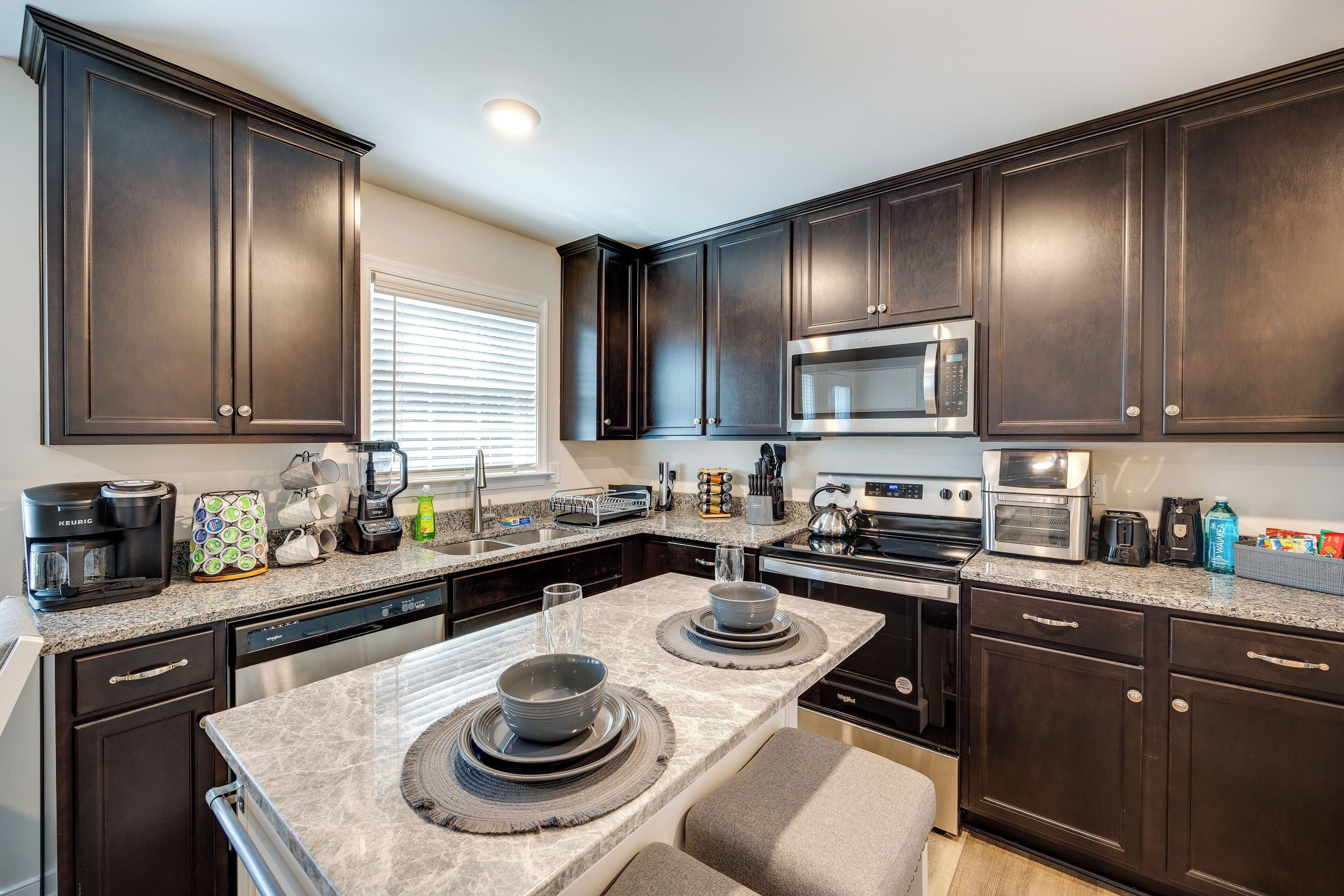 A modern kitchen with dark wood cabinets, a granite countertop, and stainless steel appliances.