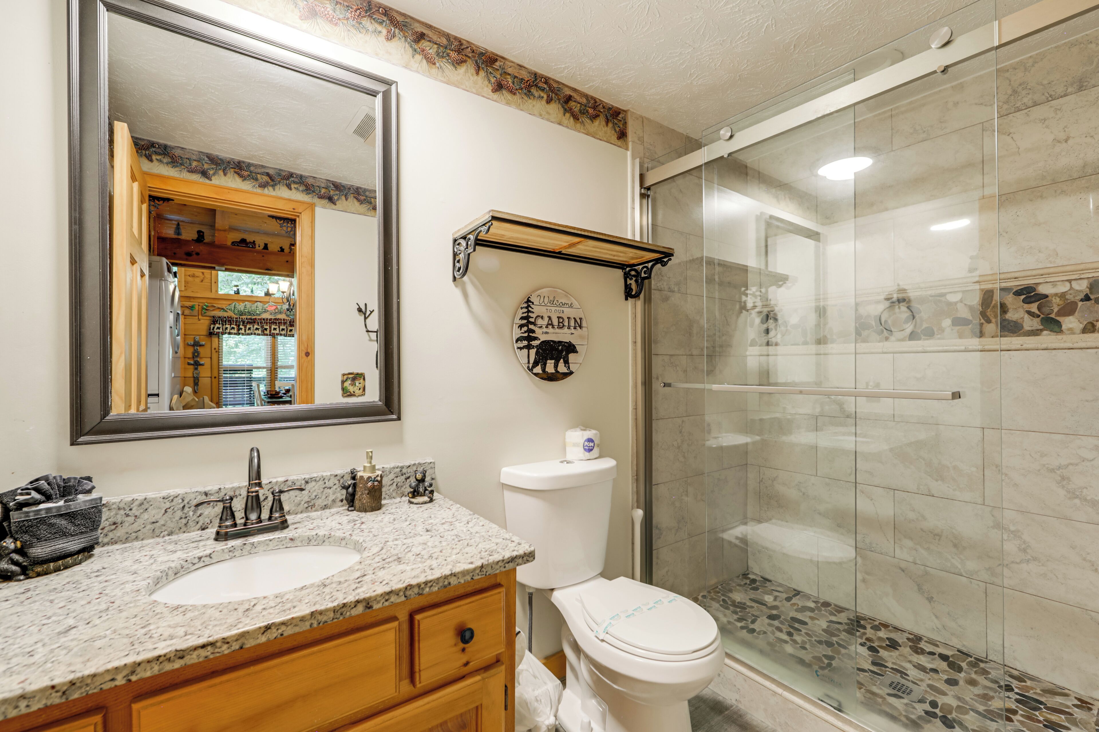 A bathroom with a sink, mirror, toilet, and shower.