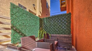 A patio area with wicker furniture and a green wall. - Oxnard Apartment < 1/2 Mi to Beaches! (Oxnard)