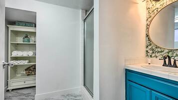 A bathroom with a white vanity, a blue cabinet, and a mirror with a floral frame.