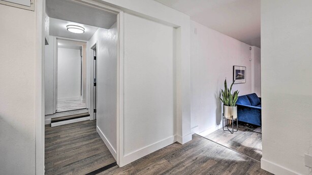 A hallway with wooden flooring, white walls, and a blue sofa with a potted plant. - Oxnard Apartment < 1/2 Mi to Beaches! (Oxnard)