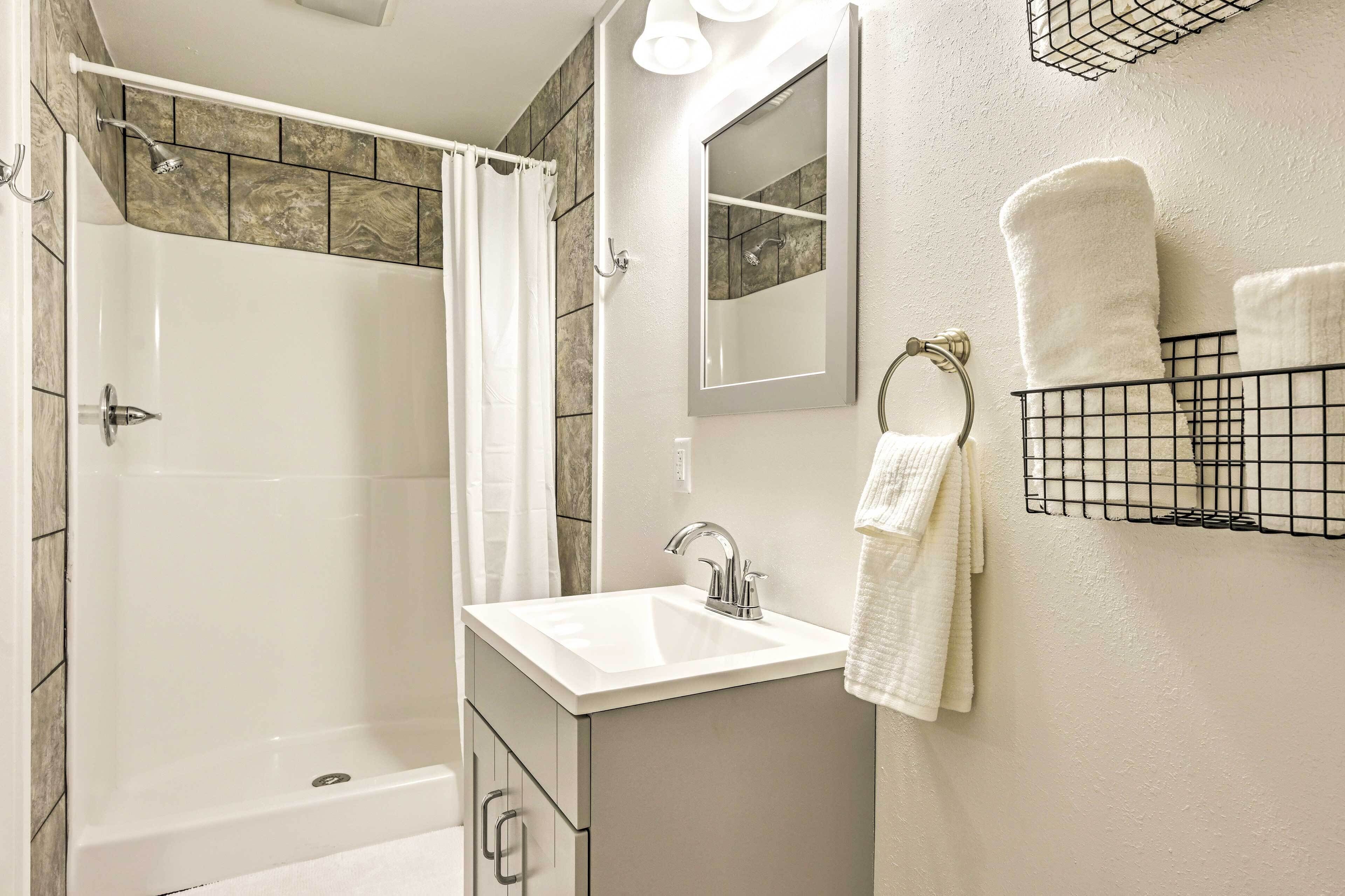 A bathroom with a shower, sink, and towel rack.