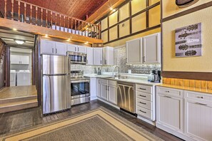 Una cucina moderna con elettrodomestici in acciaio inossidabile, mobili bianchi e una parete di fondo decorata.