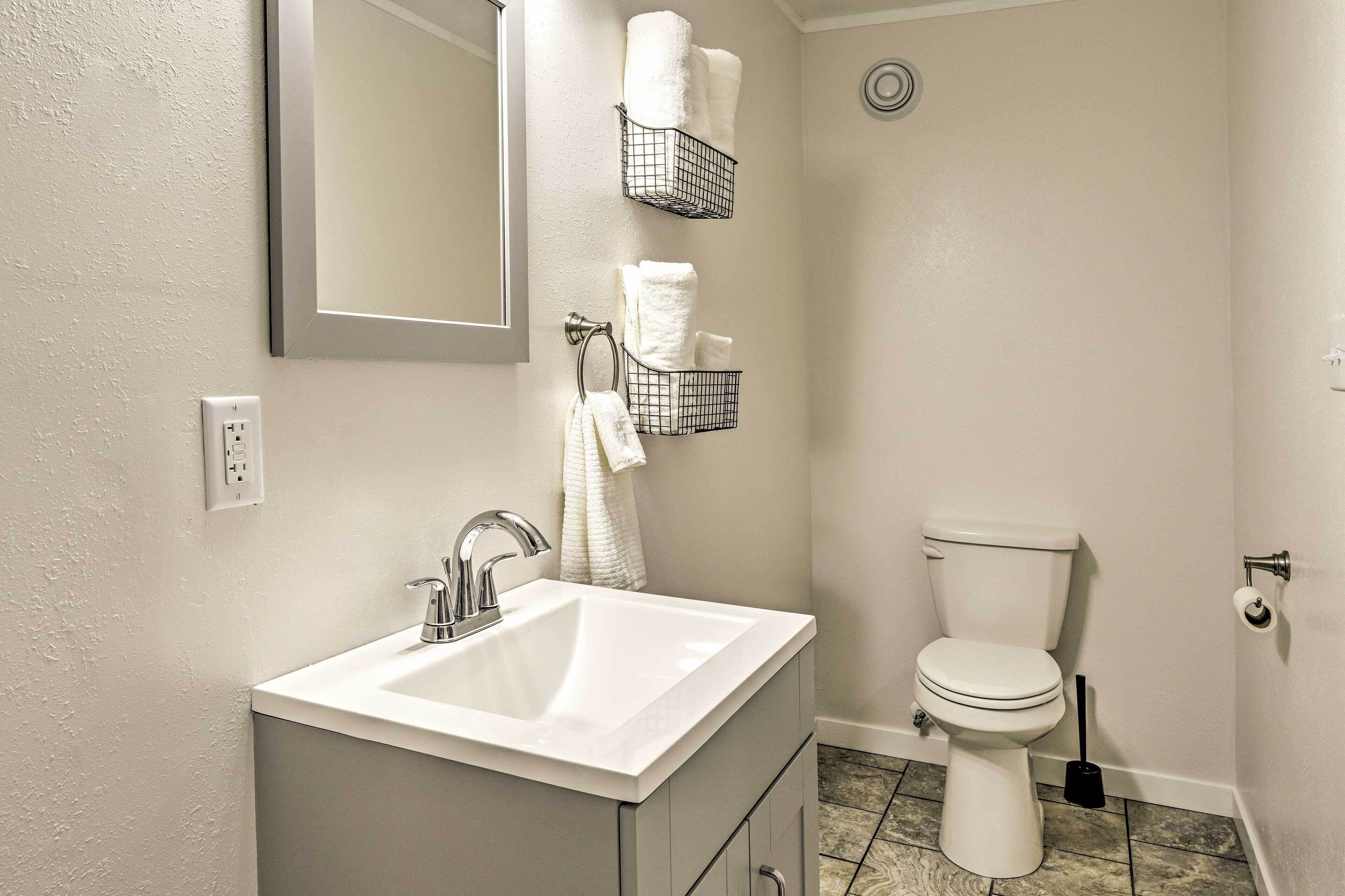 A bathroom with a white sink, a toilet, and two towel racks.