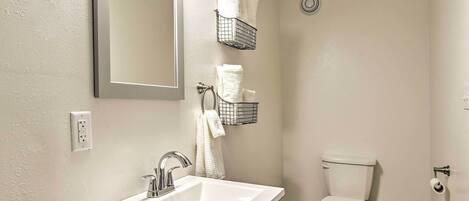 A bathroom with a white sink, a toilet, and two towel racks.