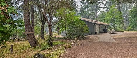 Une cabane accessible par un sentier de terre, entourée d’arbres et signalée par un panneau indiquant la présence d’un point d’eau.